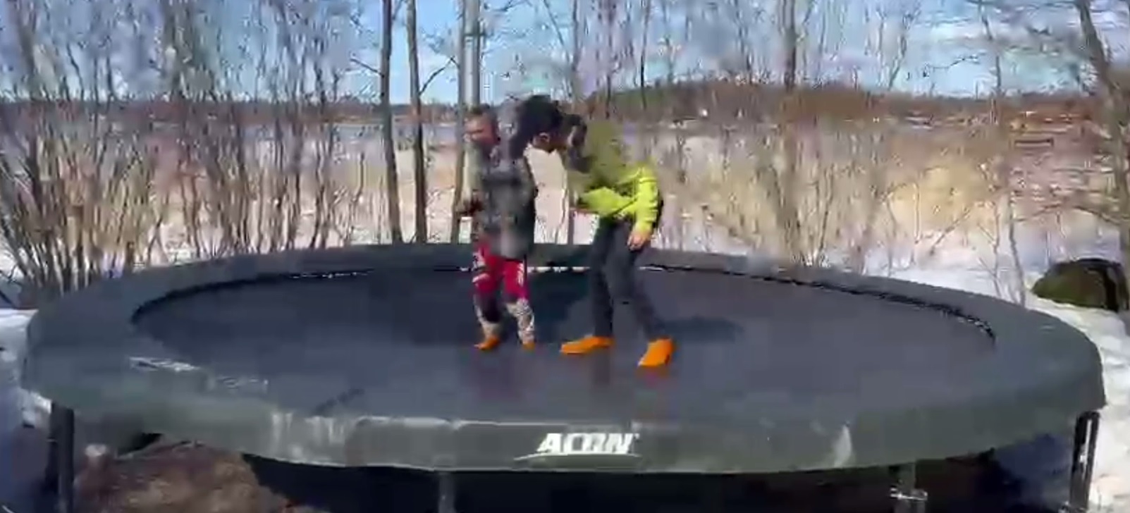Kaksi poikaa hyppimässä ulkona trampoliinilla oranssit Pitosukat jaloissaan